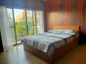 ein Schlafzimmer mit einem Bett und einem großen Fenster in der Unterkunft 韶光民泊 in Shizuoka