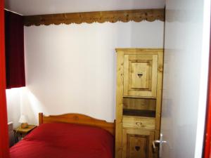 モダーヌにあるDuplex 7 pers. proche des pistes 70563の赤いベッドと木製キャビネット付きのベッドルーム1室