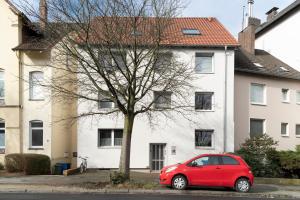 ein rotes Auto, das vor einem weißen Haus parkt in der Unterkunft Akram Appartement III - Ruhig, Stadtnah in Hildesheim