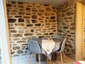 una mesa y sillas en una habitación con una pared de piedra en Gîte de France Lijoal 3 épis - Gîte de France 3 personnes 264, en Corrèze