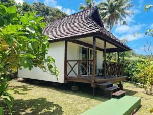 une petite maison avec une terrasse dans un jardin dans l'établissement Pension Hibiscus Taha'a, à Vaitoare