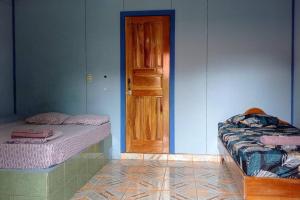 een kamer met 2 bedden en een houten deur bij Cabinas Centro Social Volio #6 in Talamanca