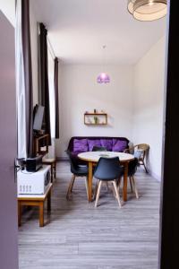 a living room with a table and a purple couch at Gîte de France Gîte ecole 3 épis - Gîte de France 4 personnes 434 in Soursac