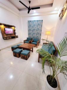 una sala de estar con sofás, una mesa y una planta en Utopiá 3BHK Entire Luxury Apartment In Noida 63, en Noida
