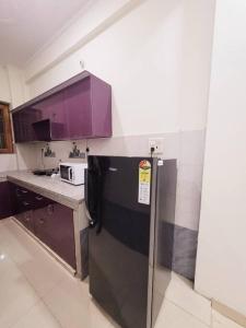 cocina con nevera negra y armarios morados en Utopiá 3BHK Entire Luxury Apartment In Noida 63, en Noida