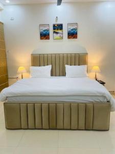 1 dormitorio con 1 cama grande con 2 lámparas y 2 cuadros en Utopiá 3BHK Entire Luxury Apartment In Noida 63, en Noida