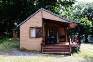 Gîte de France Chalet - Gîte de France 4 personnes 504 في Soursac: كابينة صغيرة فيها شرفة وكراسي