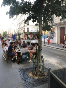 a group of people sitting at a table under a tree at APPARTEMENT QUARTIER MONTMARTRE in Paris