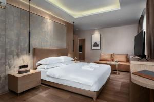 um quarto com uma grande cama branca e um sofá em SF HOTEL Penthouse Residences em Phnom Penh