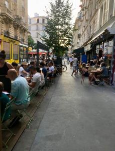 a group of people sitting at tables on a city street at APPARTEMENT QUARTIER MONTMARTRE in Paris