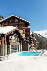 a building with a swimming pool in the snow at Résidence Les terrasses d'Eos - maeva Home - 3 Pièces 6 Personnes - Sélect 67 in Flaine