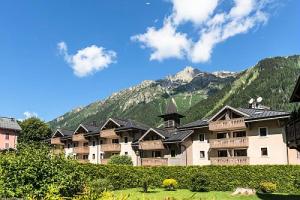 ein großes Apartmenthaus mit Bergen im Hintergrund in der Unterkunft Résidence La Ginabelle - maeva Home - 4 Pièces 6 Personnes Sélection 71 in Chamonix-Mont-Blanc