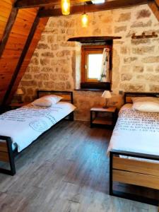 - 2 lits dans une chambre avec un mur en pierre dans l'établissement Gîte de France à Saillac 3 épis - Gîte de France 4 personnes 444, à Saillac