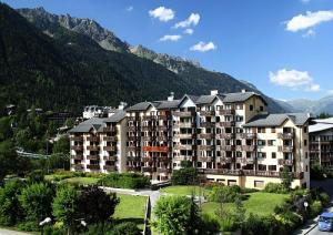 um grande edifício de apartamentos com montanhas ao fundo em Résidence La Rivière - maeva Home - Appartement 2 pièces 6 personnes - Sé 71 em Chamonix-Mont-Blanc