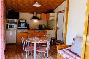 cocina y comedor con mesa y sillas en Gîte de France Chalet - Gîte de France 4 personnes 644, en Soursac