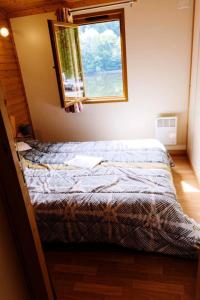 a bed in a room with a window at Gîte de France Chalet - Gîte de France 4 personnes 644 in Soursac