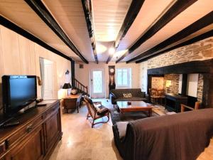 a living room with a tv and a couch at Gîte de France Au bord de l'eau 3 épis - Gîte de France 6 personnes MAE-6674 in Aubazines
