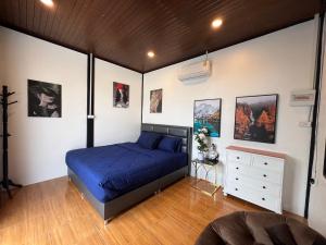 a bedroom with a blue bed and a white wall at โค้งโดนัท พรีเมียม พูลวิลล่า in U Thong