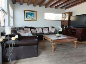 a living room with a leather couch and a coffee table at Sedgefield Lodge in Witbank