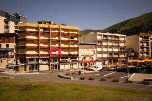 a building with a red sign in front of a parking lot at Résidence MARMOTTES - Studio pour 4 Personnes 924 in Gourette