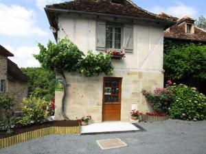 a small white house with a door and flowers at Gîte de France Gîte de la barbacane 3 épis - Gîte de France 5 personnes MAE-8884 in Curemonte