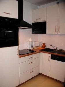 kuchnia z białymi szafkami i czarnymi urządzeniami w obiekcie Résidence CHRISTIANIA - Studio pour 6 Personnes 964 w mieście Gourette