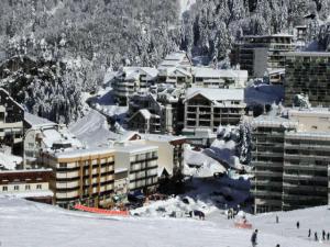 un groupe de bâtiments dans la neige avec des gens skier dans l'établissement Résidence MARMOTTES - Studio pour 6 Personnes 984, à Gourette