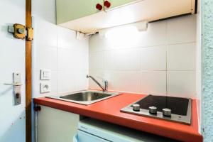 - une cuisine avec un évier et un comptoir rouge dans l'établissement Quartier Crève Cœur - maeva Home - Studio 2 personnes Confort 92, à Valmorel