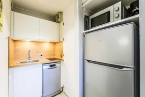 una pequeña cocina con nevera y fregadero en Résidence Pierre de Soleil - maeva Home 77590, en Aime La Plagne
