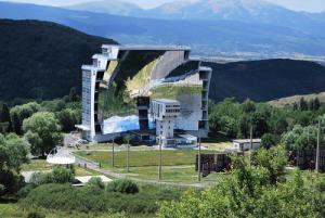 a building on top of a hill with mountains in the background at Appartement 3 pièces 7 pers avec vue magnifique sur les Pyrénées - 3 Pièces 7 personnes MAE-3855 in Font Romeu Odeillo Via