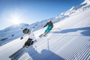two people are skiing down a snow covered slope at Résidence Neves - VAL THORENS location: Studio ensoleillé pour 4 personnes dans un quartier animé (LES NEVES) MAE-9081 in Val Thorens