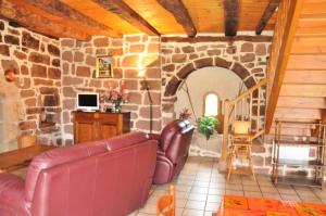 a living room with a couch and a stone wall at Gîte de France La besse 2 épis - Gîte de France 6 personnes MAE-9144 in Louignac