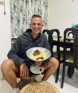 a man sitting in a chair holding a plate of food at Maple Homestay in Kohīma