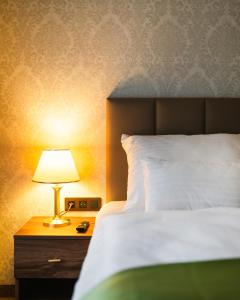 a bed with a lamp on a wooden night stand at Spa Hotel Villa Smetana in Karlovy Vary