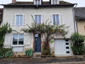 une maison avec une porte bleue et un arbre à fleurs dans l'établissement Gîte de France à Lubersac 2 épis - Gîte de France 4 personnes 304, à Lubersac