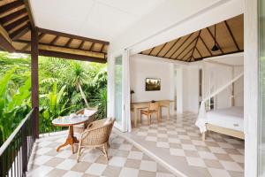 Habitación con balcón, cama y mesa. en COMO Uma Ubud en Ubud