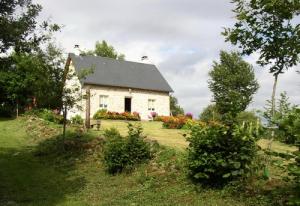 una casa blanca con un techo negro en un campo en Gîte de France à Sarroux - St Julien 3 épis - Gîte de France 6 personnes 414, en Sarroux