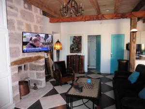 sala de estar con TV en una pared de piedra en Gîte de France Gîte la chapelle avec piscine 3 épis - Gîte de France 6 personnes MAE-9464, en Saint-Solve