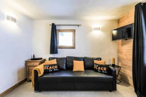 un sofá de cuero negro en una sala de estar con ventana en Quartier Crève Cœur - maeva Home - Appartement 2 pièces 6 personnes skis a 76, en Valmorel