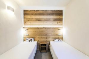 Duas camas num quarto com paredes de madeira em Quartier Crève Cœur - maeva Home - Appartement 2 pièces 6 personnes skis a 76 em Valmorel