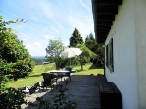 Gîte de France Le noyer 2 épis - Gîte de France 2 personnes MAE-9474 في Saint-Germain-les-Vergnes: طاولة وكراسي مع مظلة على الفناء