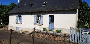 una casa bianca con piante in vaso davanti di Gîte de France "les volets bleus" épis - Gîte de France 484 a Espartignac