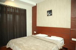 a bedroom with a bed with a wooden headboard at TAT HOLIDAYS Armaan Groups in Ooty