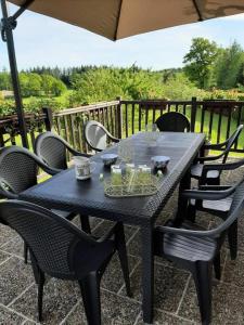 un tavolo nero con sedie e ombrellone di Gîte de France L'hyvernerie 3 épis - Gîte de France 7 personnes MAE-9504 a Gumond