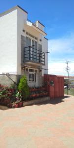 een huis met een rood hek ervoor bij TAT HOLIDAYS Armaan Groups in Ooty
