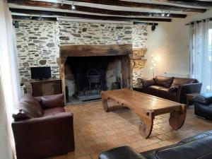 sala de estar con chimenea de piedra y mesa de madera en Gîte de France Gîte des papous épis - Gîte de France 494, en Pierrefitte