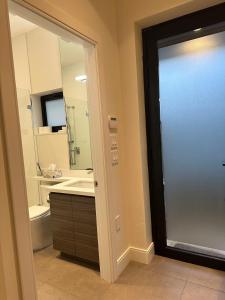ein Bad mit einer Tür, die zu einem WC und einem Waschbecken führt in der Unterkunft A Tiny House Near UBC 温哥华UBC小别墅 in Vancouver