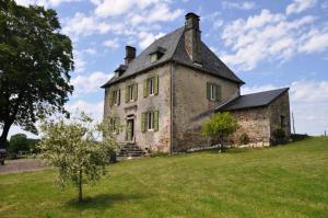 Gîte de France Laclefdeschamps 3 épis - Gîte de France 10 personnes MAE-9514 في Luc: منزل حجري قديم على تلة فيها شجرة