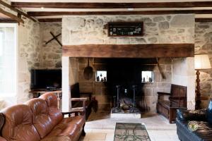 Gîte de France Laclefdeschamps 3 épis - Gîte de France 10 personnes MAE-9514 في Luc: غرفة معيشة مع أريكة ومدفأة حجرية