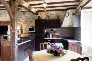 Gîte de France Laclefdeschamps 3 épis - Gîte de France 10 personnes MAE-9514 في Luc: مطبخ مع طاولة عليها مزهرية من الزهور